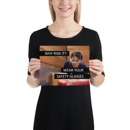 A safety poster showing a woman using a table saw to cut wood wearing safety glasses with the slogan "Why Risk It? Wear Your Safety Glasses."