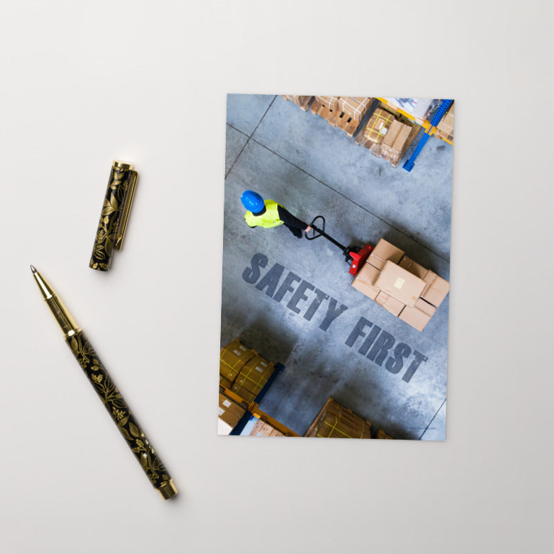 A safety print showing a bird's-eye view of a worker in a warehouse pulling boxes on a pallet jack with the slogan safety first in bold letters.