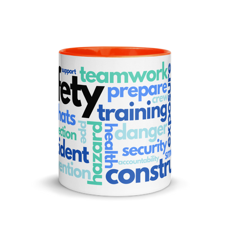 White ceramic mug with safety terms like hard hats, protection, and encourage, in a various shades of blue across the mug with an orange rim, inside, and handle.
