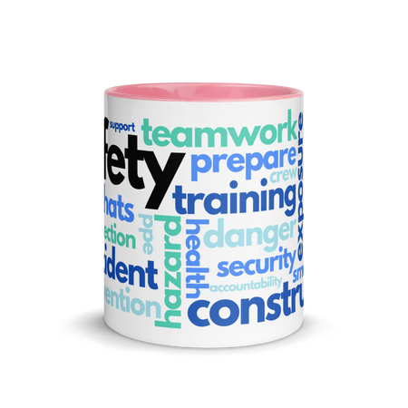 White ceramic mug with safety terms like hard hats, protection, and encourage, in a various shades of blue across the mug with a pink rim, inside, and handle.