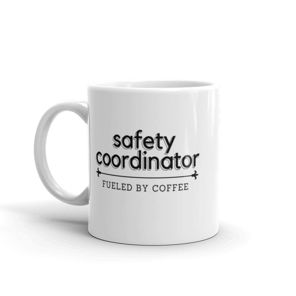 White ceramic mug with the phrase "Safety Coordinator, fueled by coffee." 