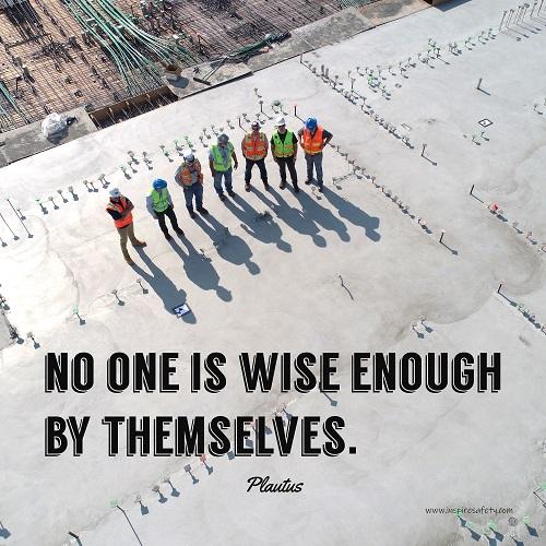 A workplace safety poster showing an aerial view of construction workers in reflective vests standing in a line on top of a building with their shadows being cast on the building with the quote no one is wise enough by themselves by Plautus.