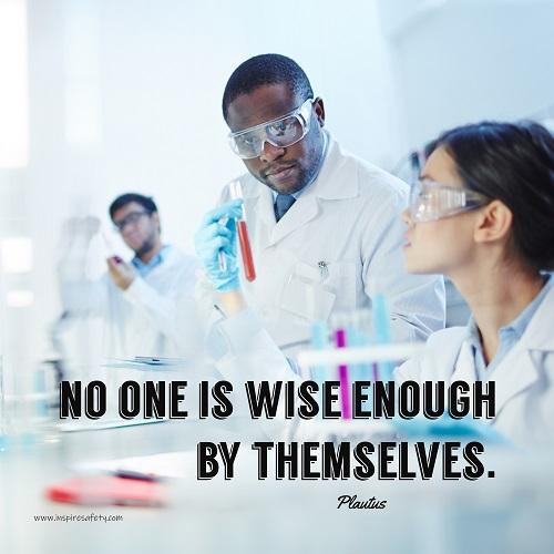 A workplace safety poster showing three scientists in white lab coats, gloves, and safety glasses working on some experiments in a stark white laboratory with the quote no one is wise enough by themselves by Plautus.