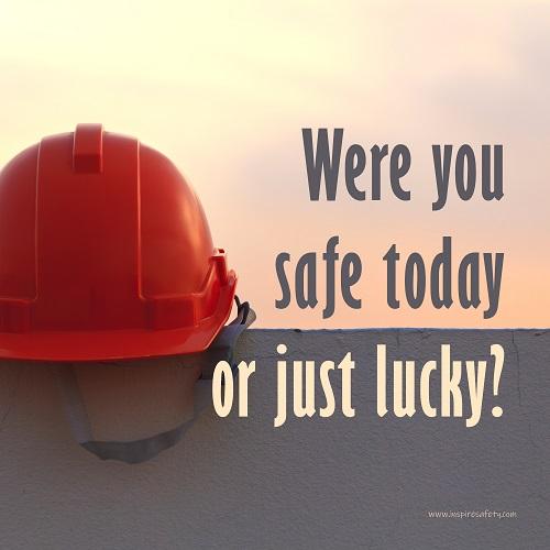 A workplace safety poster showing a red hard hat sitting on a grey wall with a dreamy sunset background and the slogan were you safe today, or just lucky?