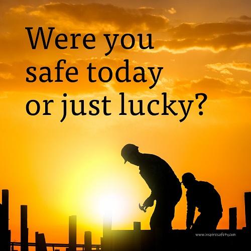 A workplace safety poster showing workers on a construction site being silhouetted in black with a sunset of orange hues in the background with the slogan were you safe today, or just lucky?