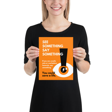 A workplace safety poster with a bright orange background an an eye with an exclamation point coming from the pupil and a lightning bolt in the middle of the pupil with text that says "See Something Say Something" in bold lettering with the words "If you see unsafe acts or workplace hazards, say something. You could save a life."