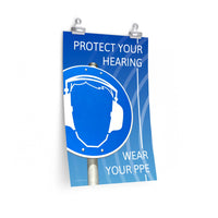 A hearing protection poster showing a bright blue construction sign with an illustration of a face wearing ear muffs with sound waves coming from the right and a safety slogan in the upper right and bottom right corners.