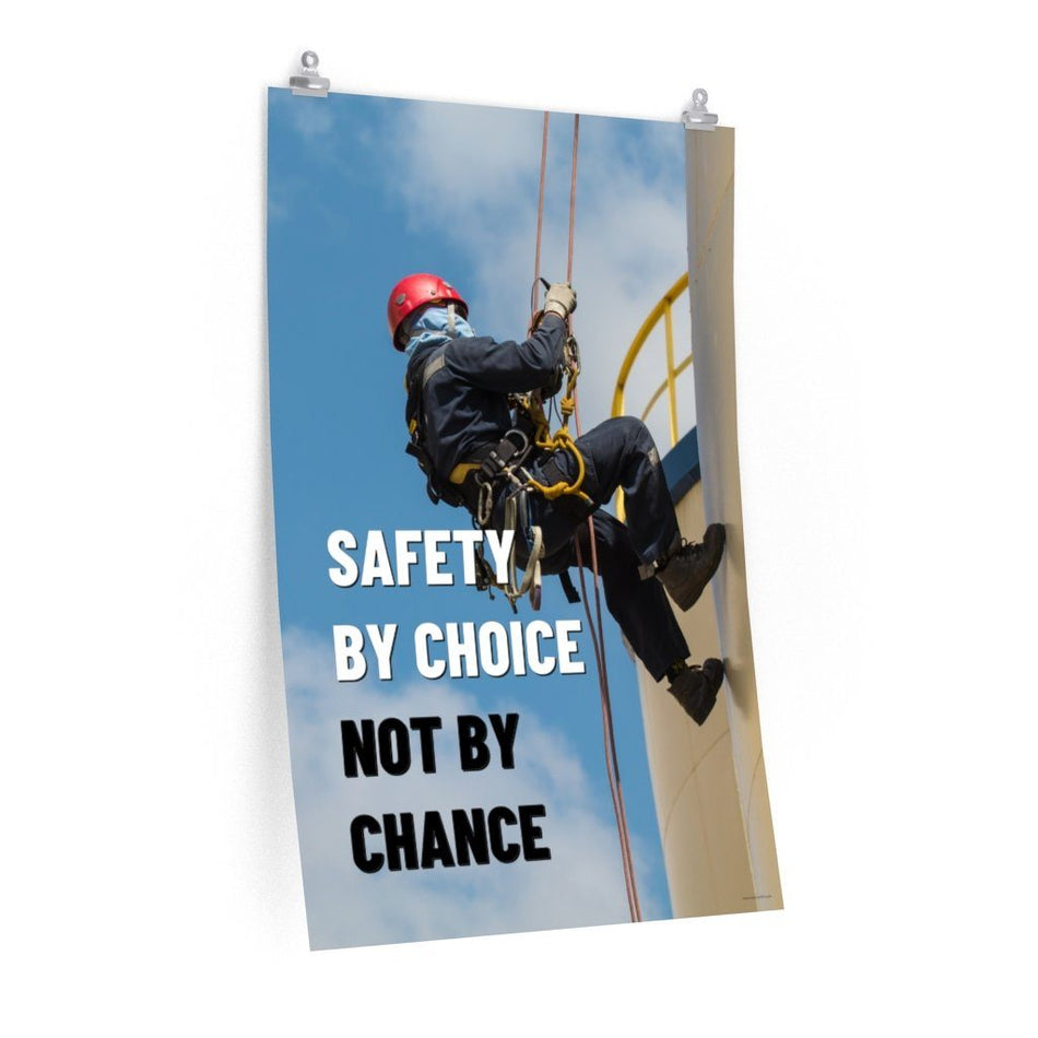 A fully harnessed man wearing a hard hat scaling the side of a building with a bright blue sky and clouds in the background with the text safety by choice, not by chance in bold text to his left.