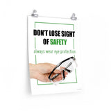An eye safety slogan showing a close up of a hand presenting out safety glasses with a safety slogan in blue text above.