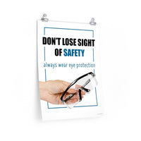 An eye safety slogan showing a close up of a hand presenting out safety glasses with a safety slogan in blue text above.