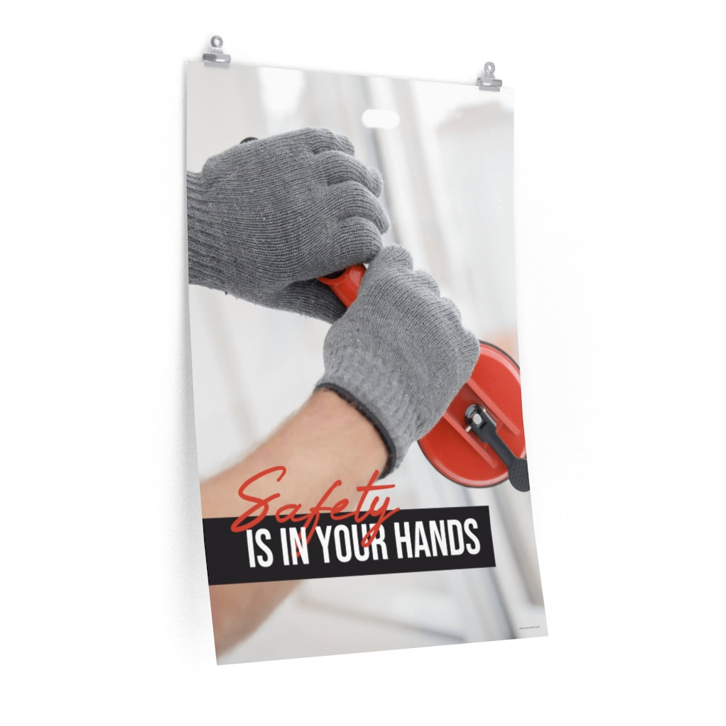 A workplace safety poster showing a close-up of a worker's hands wearing gloves while installing windows with the slogan safety is in your hands.