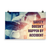 Safety poster showing a close up of 3 hands wearing gloves holding glass beakers and a safety slogan that says "Safety doesn't happen by accident" written in bottom right corner.