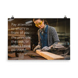 Workplace safety poster of a young female woodworker wearing safety glasses and gloves and sanding a two by four in her shop with a safety quote to the left.