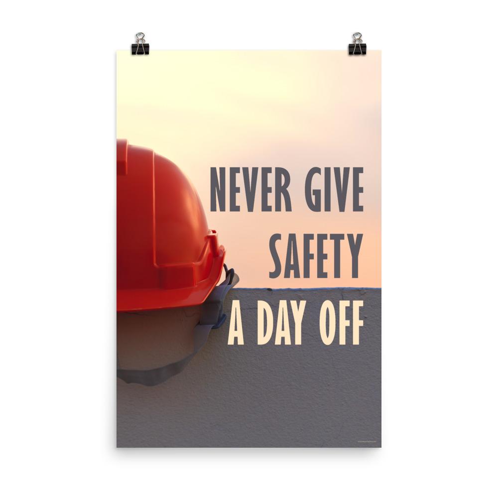 A workplace safety poster depicting a red hard hat sitting on a concrete wall with a dreamy pink sunset in the background with the text never give safety a day off to the right.