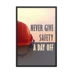 A workplace safety poster depicting a red hard hat sitting on a concrete wall with a dreamy pink sunset in the background with the text never give safety a day off to the right.