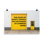 Workplace safety poster depicting a bright yellow garage door to a warehouse with a bold safety slogan on it with a smaller yellow door to the right.