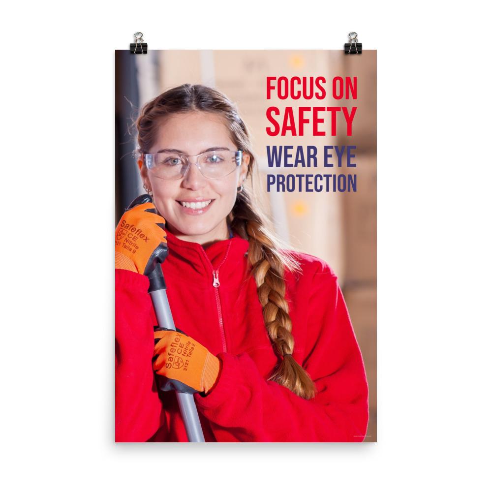 An eye safety poster of a young woman wearing safety glasses and orange gloves smiling as she works in a warehouse with a safety slogan in the top right corner.