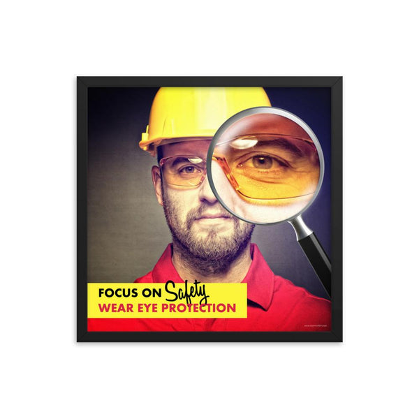 An eye safety poster showing a close up of a man's face wearing safety glasses and a yellow hard hat with a magnifying glass focusing on the right eye with an eye safety slogan underneath him.