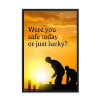 A workplace safety poster showing workers on a construction site being silhouetted in black with a sunset of orange hues in the background with the slogan were you safe today, or just lucky?