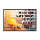 A workplace safety poster showing a yellow hard hat and some gloves sitting on a brick wall on a construction site with the slogan were you safe today, or just lucky written in black stencil font.