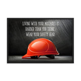 A workplace safety poster showing a bright red hard hat with an ominous black background with the slogan living with your mistakes is harder than you think, wear your safety gear.