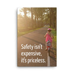 A safety poster showing a little girl riding her bike down a road on a sunny day with the slogan safety isn't expensive, it's priceless.