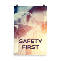 A safety poster showing a close-up of multiple gloved hands in a laboratory pouring substances into a beaker with the slogan safety first in the foreground.