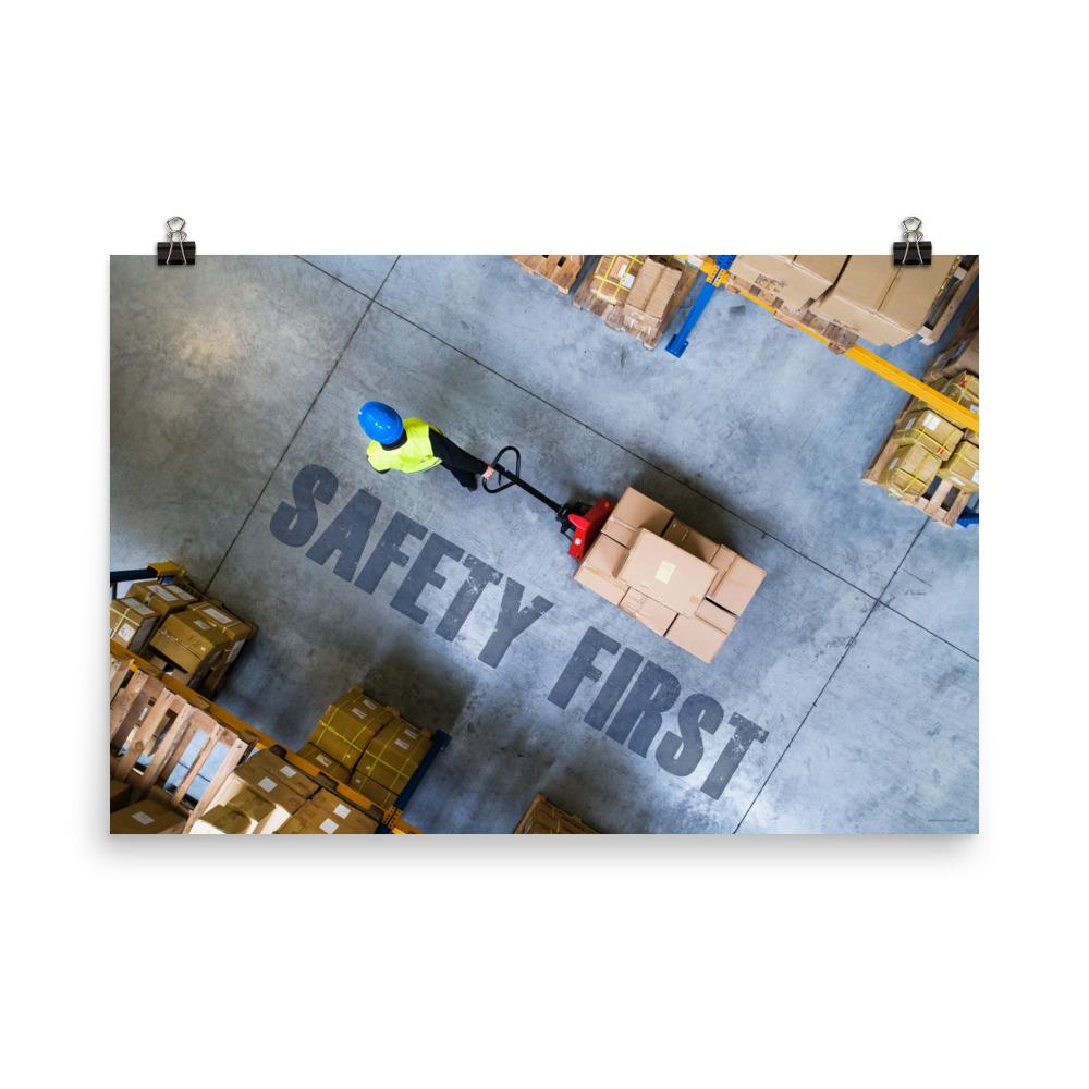 A safety poster showing a bird's-eye view of a worker in a warehouse pulling boxes on a pallet jack with the slogan safety first in bold letters.