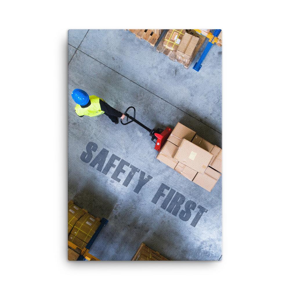 A safety poster showing a bird's-eye view of a worker in a warehouse pulling boxes on a pallet jack with the slogan safety first in bold letters.