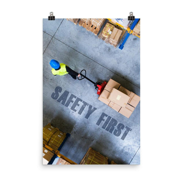 A safety poster showing a bird's-eye view of a worker in a warehouse pulling boxes on a pallet jack with the slogan safety first in bold letters.