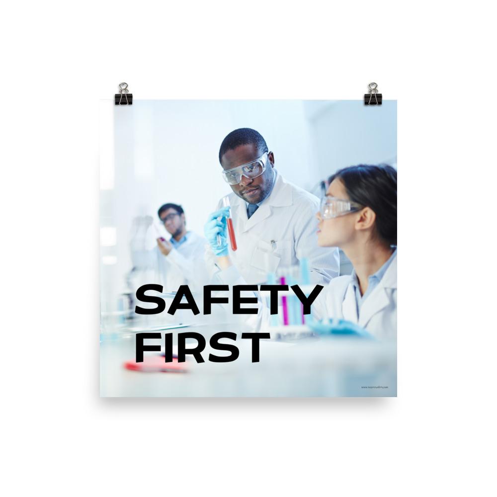 A safety poster showing two lab workers collaborating on a project in a lab while wearing full PPE with the slogan safety first.