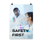 A safety poster showing two lab workers collaborating on a project in a lab while wearing full PPE with the slogan safety first.