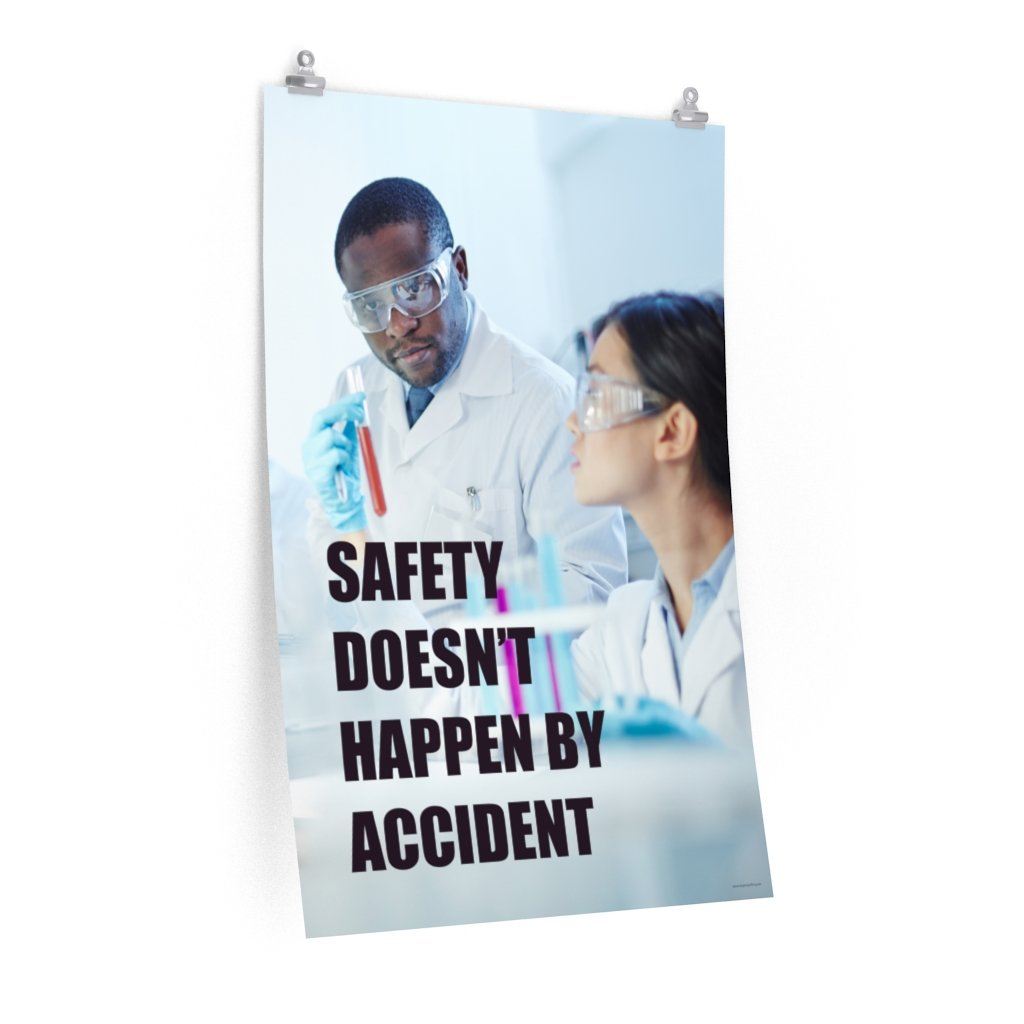 Male and female workers wearing lab coats and safety glasses while inspecting a test tube with a safety slogan written in bold text.