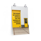 Workplace safety poster depicting a bright yellow garage door to a warehouse with a bold safety slogan on it with a smaller yellow door to the right.