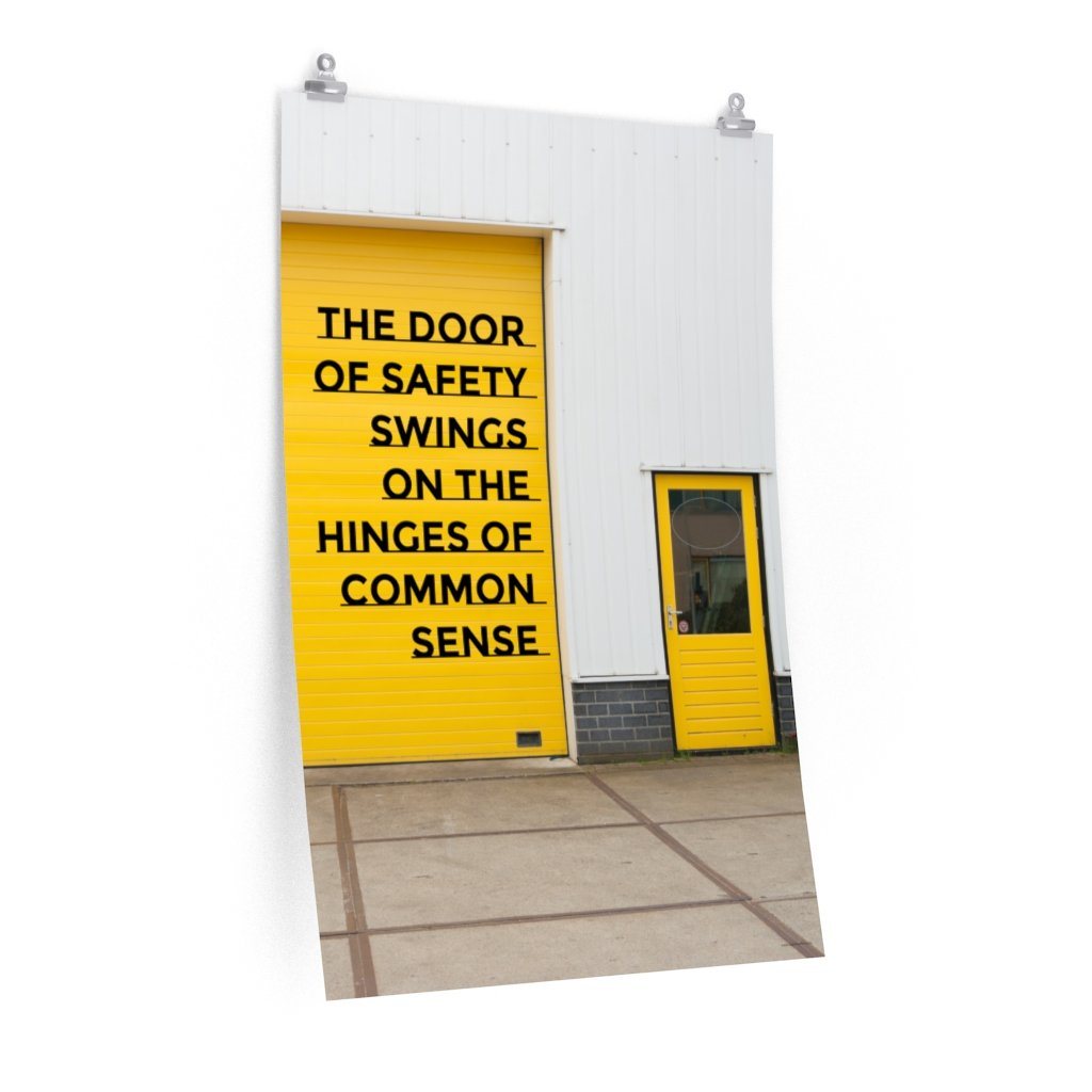 Workplace safety poster depicting a bright yellow garage door to a warehouse with a bold safety slogan on it with a smaller yellow door to the right.