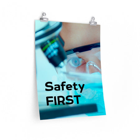 A safety poster showing a close up of a lab worker's eyes examining a sample on a microscope while wearing safety glasses and a mask with the slogan safety first in bold letters.