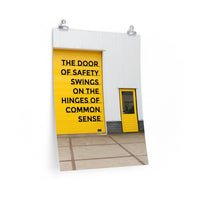 Workplace safety poster depicting a bright yellow garage door to a warehouse with a bold safety slogan on it with a smaller yellow door to the right.