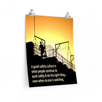 A construction safety poster showing the silhouette of a construction worker working on a building with a bright yellow sunset in the background and a safety slogan in the bottom left corner.