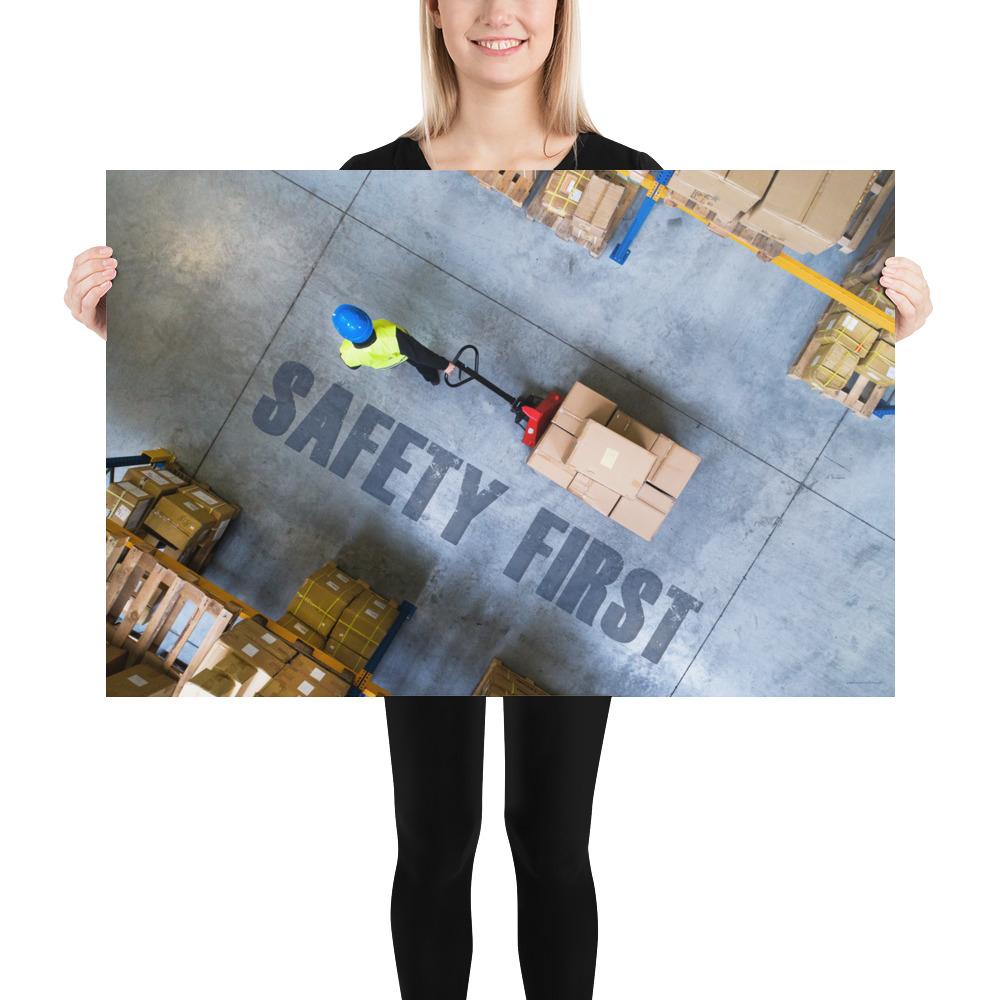 A safety poster showing a bird's-eye view of a worker in a warehouse pulling boxes on a pallet jack with the slogan safety first in bold letters.