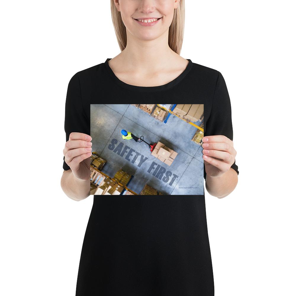 A safety poster showing a bird's-eye view of a worker in a warehouse pulling boxes on a pallet jack with the slogan safety first in bold letters.