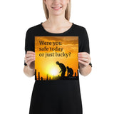 A workplace safety poster showing workers on a construction site being silhouetted in black with a sunset of orange hues in the background with the slogan were you safe today, or just lucky?