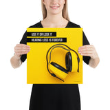A hearing protection safety poster depicting bright yellow ear muffs on a bright yellow background in the bottom right corner with a bold safety slogan in the upper left corner.