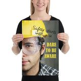 Safety poster showing a close up on half of a man's face wearing a yellow hard hat and safety glasses with text to the right.