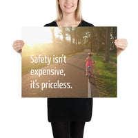 A safety poster showing a little girl riding her bike down a road on a sunny day with the slogan safety isn't expensive, it's priceless.