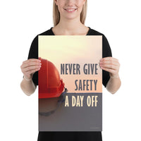 A workplace safety poster depicting a red hard hat sitting on a concrete wall with a dreamy pink sunset in the background with the text never give safety a day off to the right.