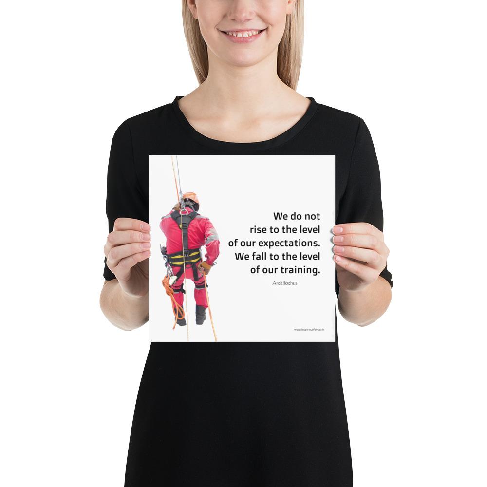 A safety poster showing a worker performing a controlled descent while wearing a fall protection harness on a bright white background with a quote from Archilochus to the right.