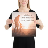 A workplace safety poster showing a father and his young daughter walking on the shore of a beach with a beautiful sunset in the background and text saying safety is a small investment for a rich future.