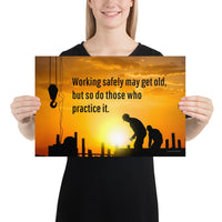 A workplace safety poster showing a construction site and construction workers being silhouetted by a bright and beautiful sunset of different shades of orange with the slogan working safely may get old, but so do those who practice it.