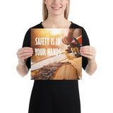 A safety poster showing a close-up of a man's hands holding a chainsaw sawing through a log with sawdust flying everywhere with the text safety is in your hands to the left.