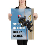 A fully harnessed man wearing a hard hat scaling the side of a building with a bright blue sky and clouds in the background with the text safety by choice, not by chance in bold text to his left.
